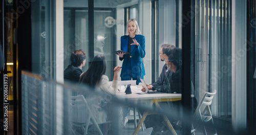 Tableau sur toile Female Business Leader Stands at the Front of a Glass Conference Room, Using a D