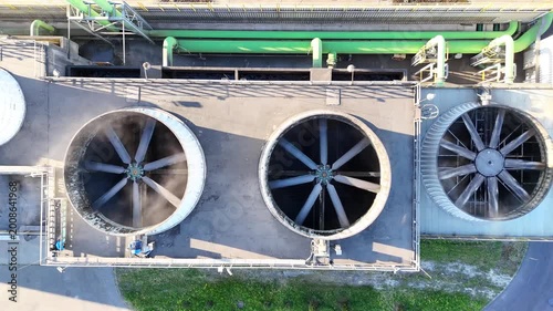Aerial view of industrial cooling system with large fans and green ventilation units on a factory roof, showcasing continuous airflow and operational efficiency in a manufacturing environment