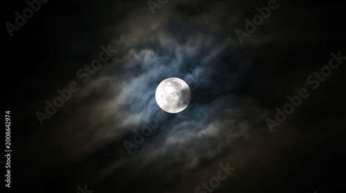 Bright full moon glowing in the dark night sky surrounded by soft flowing clouds