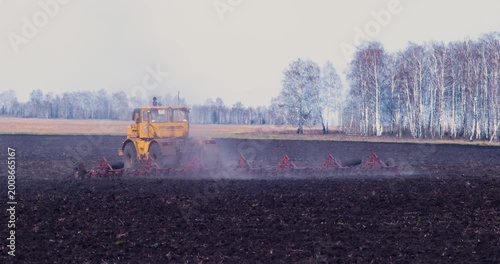 A yellow tractor plows the field. The contrasting colors of soil and crop form a stunning tapestry, illustrating the harmony between man and the land in agriculture. Modern farming. 4k video.