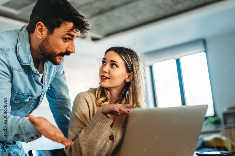 Fototapeta premium Man and woman working remotely using laptop. Male female freelancers working together. Digital nomad