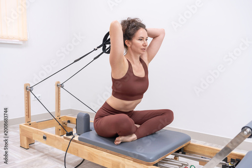 Bild auf Leinwand Pilates reformer workout woman practicing core exercises on equipment in a brigh