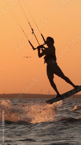 professional kitesurfer executing high jump trick sunset silhouette slow motion extreme water sports mastery