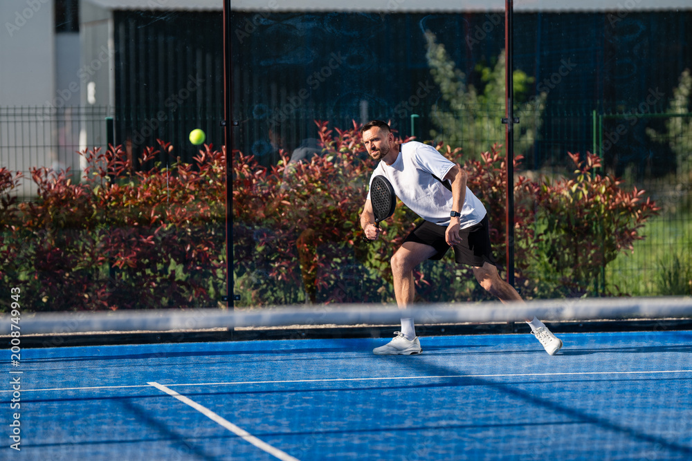 Fototapeta premium Male padel player hitting ball during match