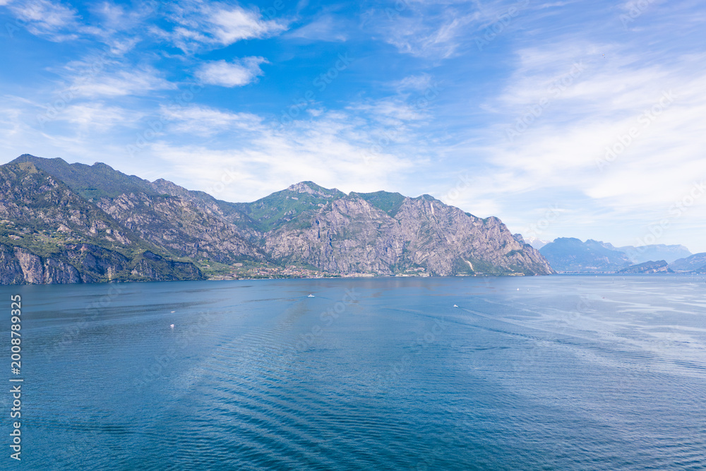 Obraz premium Lake Garda with mountain landscape and coastal town. Wide water surface and alpine scenery in northern Italy travel destination
