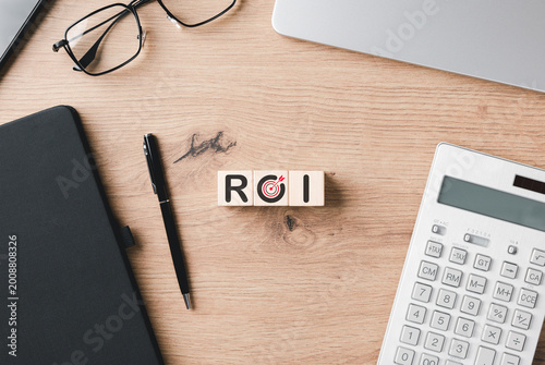 Fotografie ROI return on investment concept featuring wooden blocks on an office desk with calculator and notebook to represent financial growth, profit analysis, and successful business goal marketing