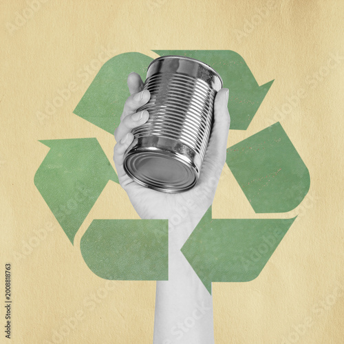 Hand holding a metal can against a green recycle symbol for sustainability