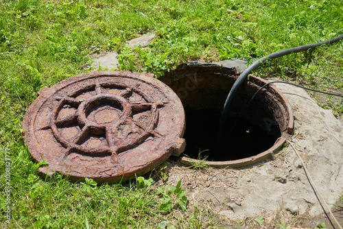 Canvas-taulu Pumping sewage from septic tank, open rusty manhole and hose pumping out sewage