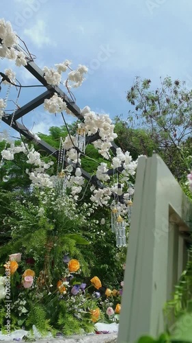 Cinematic shot of floral decoration against blue sky in garden setting. Bright natural lighting enhances color and atmosphere, perfect for wedding, celebration, and outdoor lifestyle visuals.