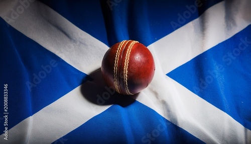 light shining on red cricket ball placing on scotland flag in the dark