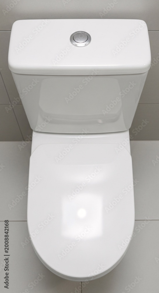 Fototapeta premium Modern white toilet in bathroom overhead view on gray tiles background