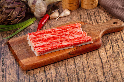 Photos Imitation Crab Sticks on Wooden Cutting Board with Fresh Vegetables