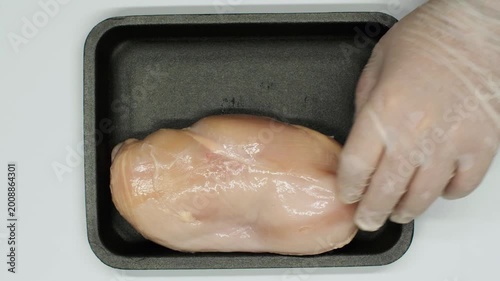 Hands place a chicken breast into a Styrofoam container isolated on a white background. Factory packaged chicken meat. Chicken meat package.
