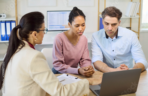Couple and advisor in finance consultation meeting. They review mortgage options, loan terms and planning with clear discussion toward agreement. Concept of financial guidance and trust.