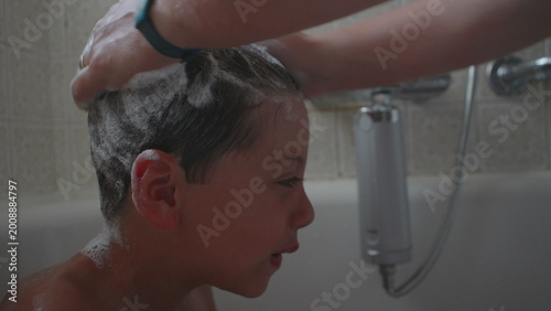 Fotografie Mother washing child’s hair with shampoo, creating foam and lather during bath t