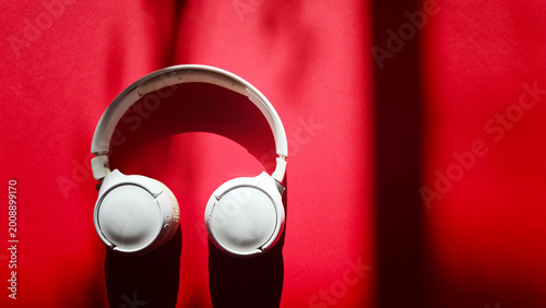 Fotografija White over-ear headphones positioned on a vibrant red surface, with soft shadows