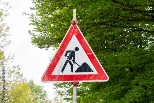 Road Work Warning Traffic Sign with Worker Symbol on Roadside in Nature