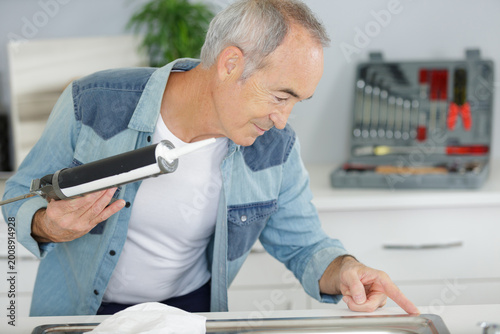 Photography a senior man repairing kitchen