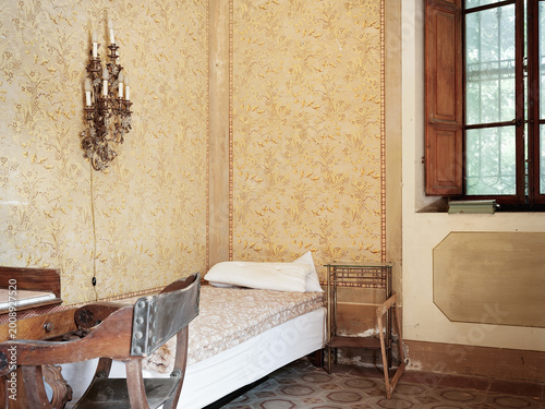 Vintage bedroom with ornate wallpaper and single bed in historic interior