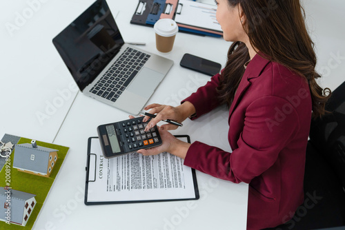 Real Estate Agent Using Calculator and Laptop at Office Desk