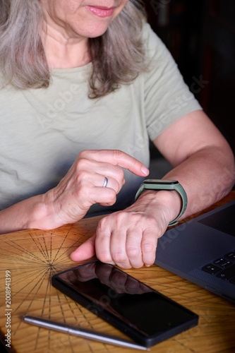 Elderly woman using a fitness tracker at home