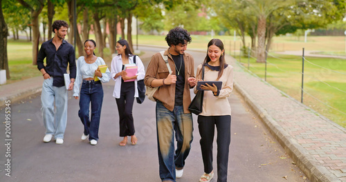 Indian young adult gen z busy boy girl use tab look screen talk share new online e learning study plan place. pupil female male man group speak funny gossip enjoy break day have fun joy park