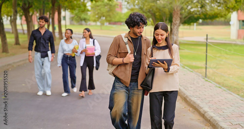 Fotografia Indian young adult gen z busy boy girl use tab look screen talk share new online e learning study plan place
