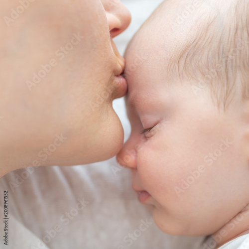 Obraz na plátně Mother kissing forehead of sleeping newborn baby