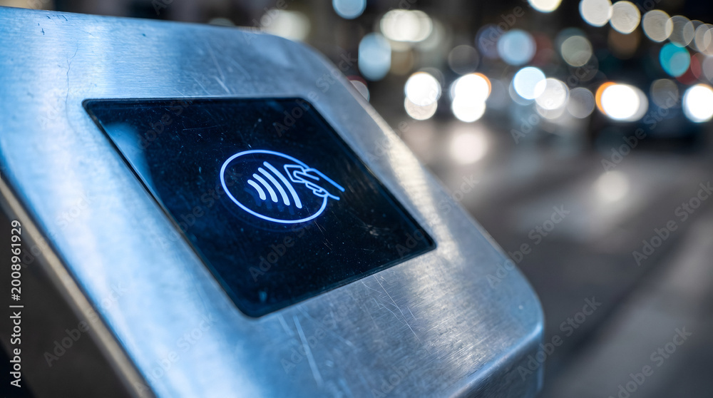 Obraz premium contactless payment symbol on public transport charging pad with city lights background