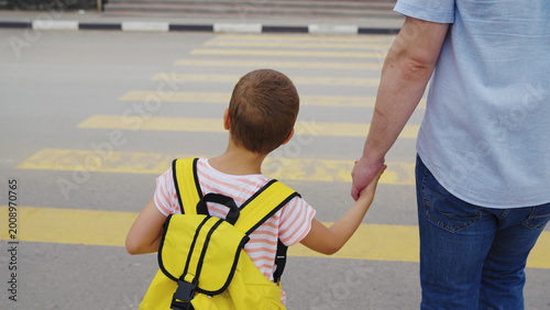 Kid and parent crossing yellow lines, Family values in action, School commute in the city, Child’s safety on the road, Urban safety for children, Father and son bonding time, Keeping children safe