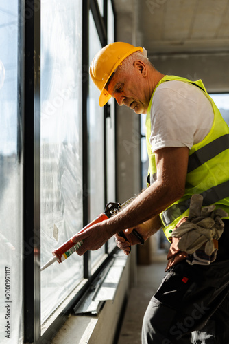Worker Applies Sealant to Window in a Building During Daylight Hours for Construction Project