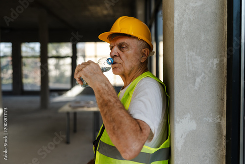 Construction Worker Takes a Break to Drink Water in Empty Building During the Afternoon