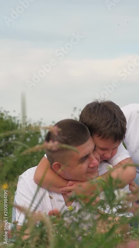happy baby hugs dad outdoors, happy family, cheerful parent child relaxing green summer meadow, picnic outdoors, summer adventures, wife husband parent son child hugging together outdoors, smile face