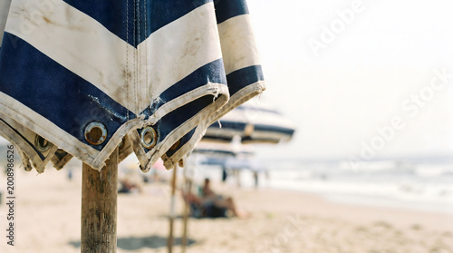 Foto close-up of striped beach umbrella tied to wooden pole on sandy shore