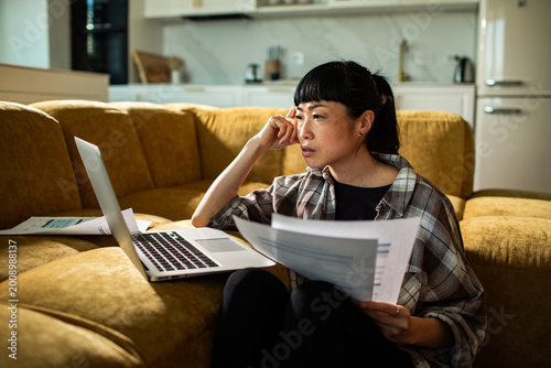 Concerned woman reviewing bills on laptop at home
