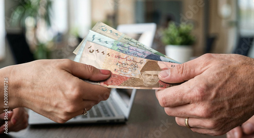 Bild auf Leinwand Close Up of Hands Exchanging Pakistani Rupee Banknotes Indoors – Pakistan Curren