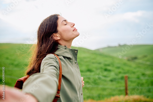 Tableau sur toile Woman standing in green meadow with eyes closed, breathing deeply and finding pe