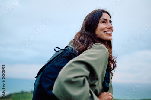 Photos Young woman smiling, looking away while hiking outdoors, enjoying the fresh air