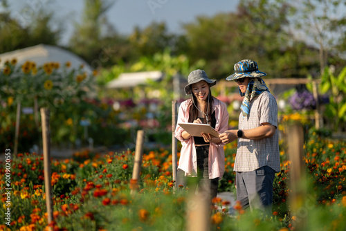 Young farmers using digital tablet inspecting flower farm