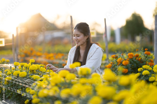 Woman happily caring for marigold flowers in garden at sunset