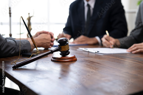 Fotografie Lawyers discussing and signing legal contract with gavel on table