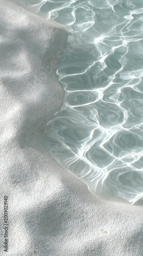 Gentle water ripples shimmer on the soft white sand at a peaceful beach. The sunlight glimmers on the surface, blending tranquility with the rhythmic sound of waves