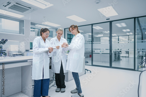 Fotografia Diverse biotech research team analyzing experimental data metrics on digital tablet
