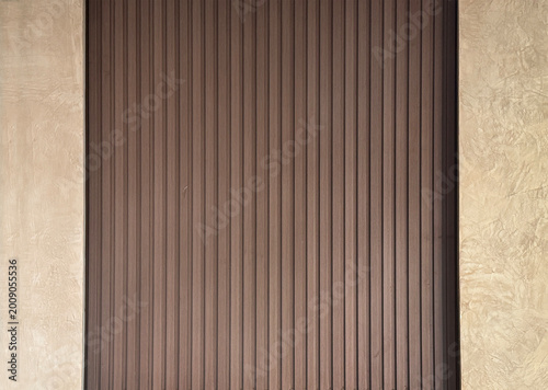 Close up of lime wash beige textured paint combined with brown fluted wood. For wall panel finishes, wall covering, and interior design material. Seamless background texture.