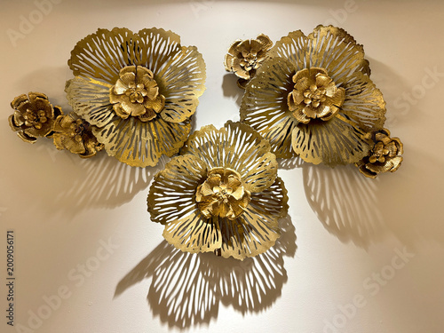 Close up of wrought iron sculpture, gold metal flower art as wall decoration or accessories. Antique iron crafts with layered petals and intricate details for modern interior decoration.
