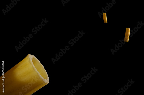 Rigatoni pasta tube drifting in a black vacuum, space station silhouette concept.