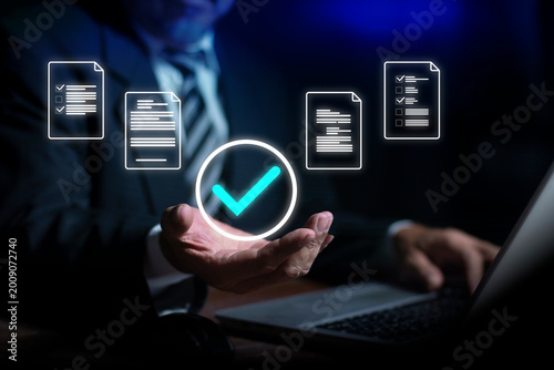 Businessman holding glowing check mark symbol surrounded by floating documents. symbolizing approval and Safeguard your valuable data and personal information with cutting-edge cyber security.