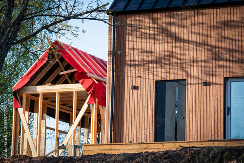 House Extension Under Construction Next to Modern Wooden Home Exterior