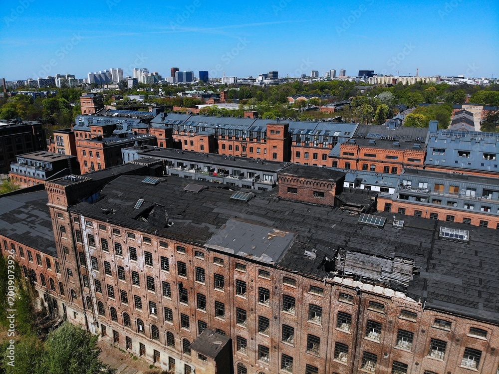 Fototapeta premium Lodz city in Poland. Lodz industrial heritage with renovated historic Scheibler textile factory in background and deteriorated abandoned second factory in foreground.