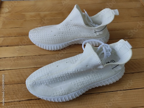 White fabric sneakers on the wooden background